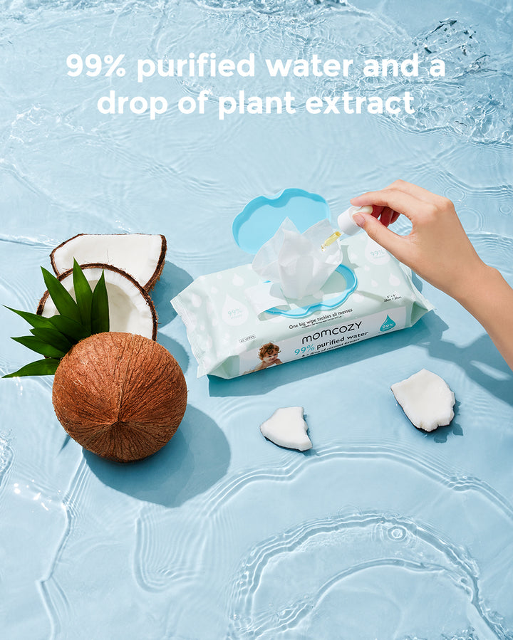 Momcozy 99% purified water wipes on a water surface with a hand holding a dropper and a split coconut beside. Text reads '99% purified water and a drop of plant extract.'