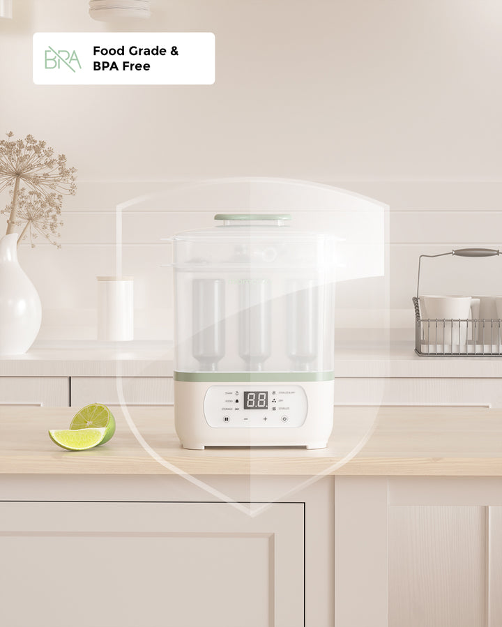 8-in-1 Baby Bottle Steam Sterilizer on kitchen counter with LED countdown display, labeled Food Grade & BPA Free, with a cut lime and vase in the background.