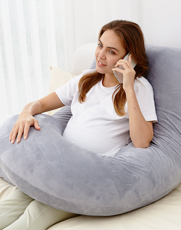 Maman se reposant avec un coussin de grossesse Momcozy dans une chambre chaleureuse