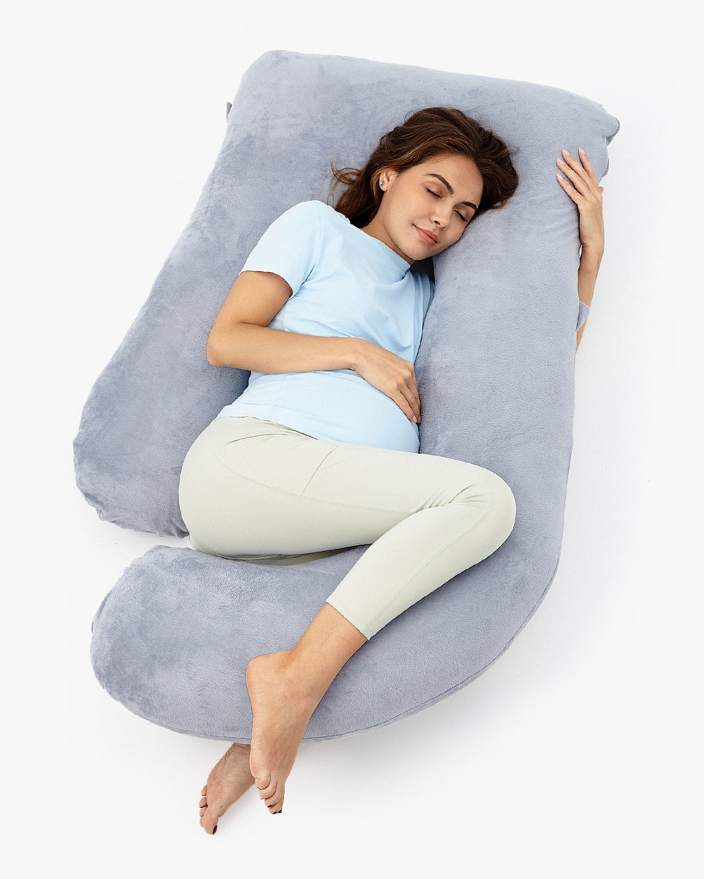 Pregnant woman resting comfortably on a gray U-shaped maternity body pillow, offering support and promoting restful sleep.