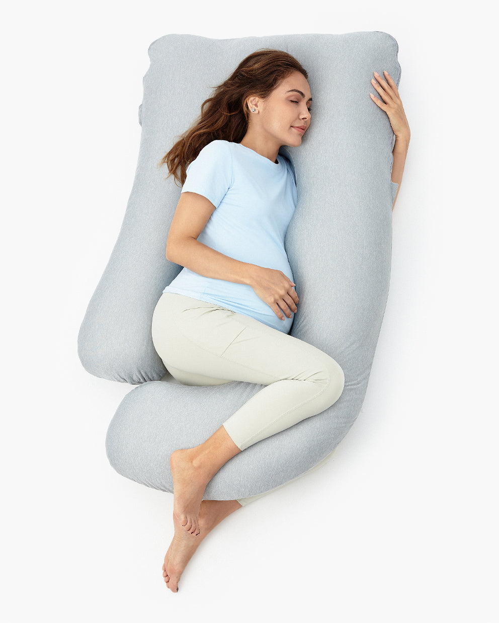 Pregnant woman resting on a light gray U-shaped maternity body pillow for pregnancy comfort and restful sleep
